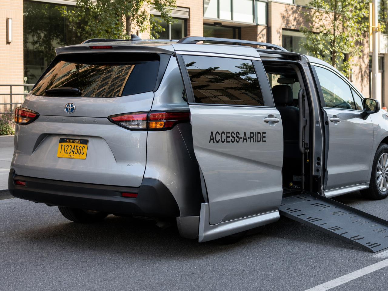 Driver assisting a passenger in a wheelchair up the ramp of a TG Texport accessible van